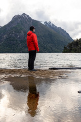 Reflection of a traveler with a red jacket at the Hidden Lake in Bariloche, Patagonia, Argentina