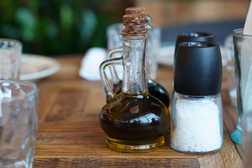 Bottle with vinegar, salt and napkins on a wooden table in a restaurant.