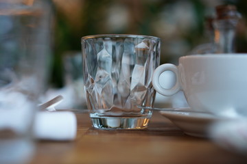 Empty transparent glass cup on a wooden table in a restaurant.
