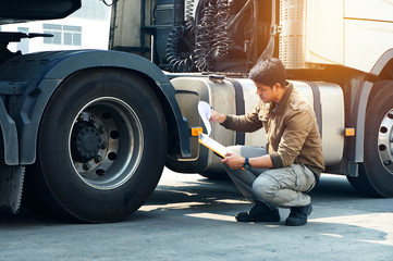 Obraz na płótnie Canvas Asian Truck Drivers is Checking the Truck's Safety Maintenance Checklist. Lorry Driver. Inspection Truck Safety of Semi Truck Wheels Tires. Auto Service Shop. 