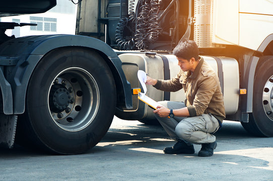 Asian Truck Drivers Is Checking The Truck's Safety Maintenance Checklist. Lorry Driver. Inspection Truck Safety Of Semi Truck Wheels Tires. Auto Service Shop. 	