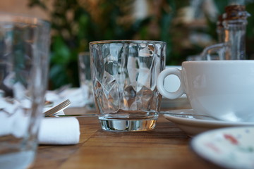 Empty transparent glass cup on a wooden table in a restaurant.