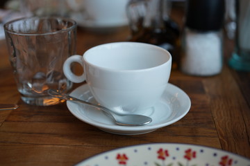 Empty white cup for tea or coffee on a wooden table in a restaurant.
