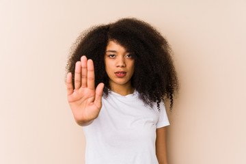 Young african american woman standing with outstretched hand showing stop sign, preventing you.