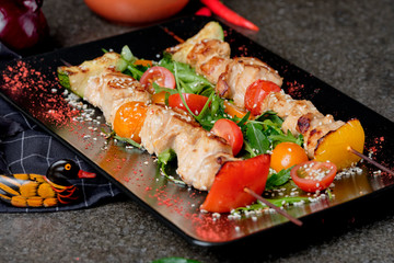 Grilled kebabs with red pepper, tasty spicy, onion and colorful vegetable on black plate, stone background. Top view bbq meat chicken kebab. Close up, selective focus.