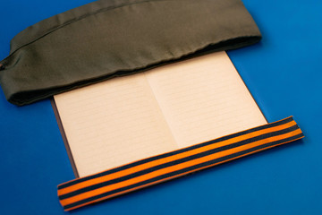 May 9. VICTORY DAY. St. George's ribbon, notebook, wooden stars, military cap. Wooden background. Victory, memory, the concept of veterans.