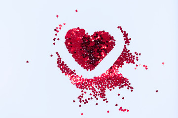 Red sparkles in the shape of a heart on a white background. Concept for Valentine's Day. Flatlay, topview