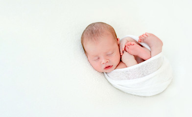 Cute newly arrived baby lying, wrapped in blanket