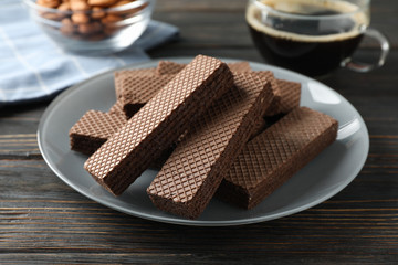 Wafers, cup of coffee and almond on wooden table, close up
