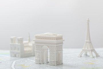 selective focus of arc de triomphe near small figurines on map of paris isolated on grey