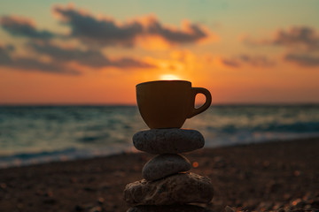 Cup on the beach against the background of sunsets. Sun in a Cup