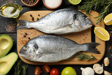Cutting board with Dorado fishes and cooking ingredients on wooden background, top view Cutting board with Dorado fishes and cooking ingredients on wooden background, top view
