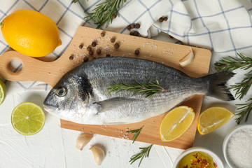 Cutting board with Dorado fish and cooking ingredients on white background, top view