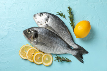 Fresh Dorado fishes, lemon and rosemary on blue background, top view