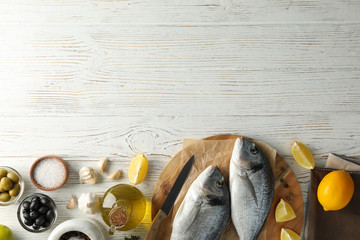 Board with Dorado fishes and cooking ingredients on wooden background, top view