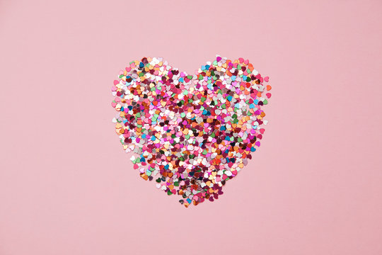 Valentine day composition with heart made from confetti on pink background, flat lay