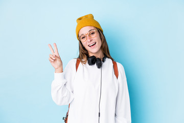 Young student woman isolated joyful and carefree showing a peace symbol with fingers.