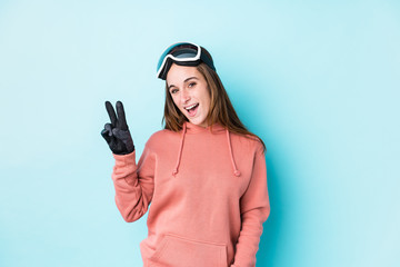 Young skier woman isolated joyful and carefree showing a peace symbol with fingers.