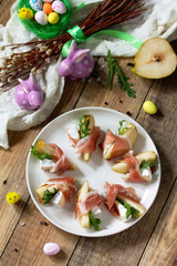 Festive snacks. Pear appetizer with jamon, arugula and brie cheese on a rustic wooden table.