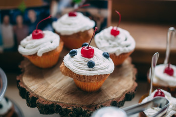 Cupcakes with cherrie and blueberries on wooden stand