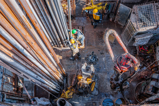 Offshore Oil Rig Worker Prepare Tool And Equipment For Perforation Oil And Gas Well At Wellhead Platform. Making Up A Drill Pipe Connection. A View For Drill Pipe Connection From Between The Stands