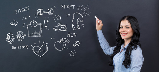 Fitness and diet with young woman writing on a blackboard