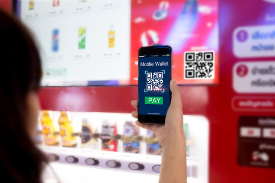 Mobile wallet concept.Woman hands scaning QR code via mobile phone with Smart Vending machine as background
