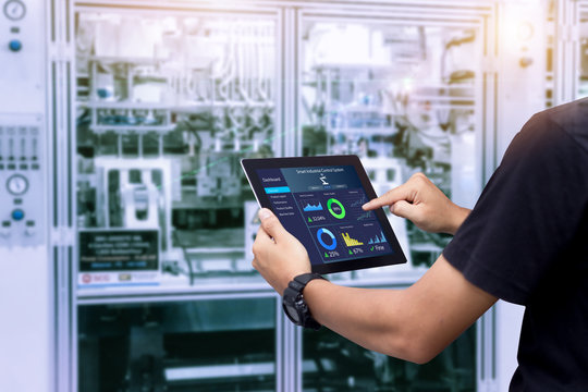 Smart industry control concept.Hands holding tablet on blurred automation machine as background