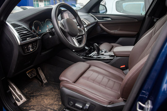 Empty Interior Of The Modern Premium Series Car. Brown Leather Driver's Seat. Dirty Interior, Carpets In The Mud. Close-up, Soft Focus