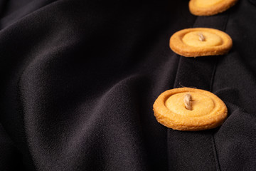 Cookies button with threads, on a black background, fabric, shirt.