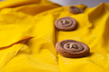 Cookies button with threads on a yellow cloak. Arranged in a row.