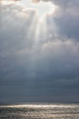 Rays of light through clouds Shine a spot on the sea, from heaven to earth