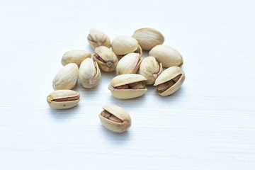  Pistachios on the white wooden background, accompanied by green leaf