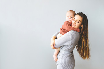 Happy mother holding up her baby girl. Young beautiful mother holds her baby and cuddles, motherhood concept - obrazy, fototapety, plakaty