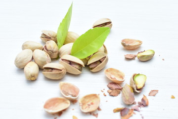  Pistachios on the white wooden background, accompanied by green leaf