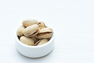  Pistachios on the white wooden background, accompanied by green leaf