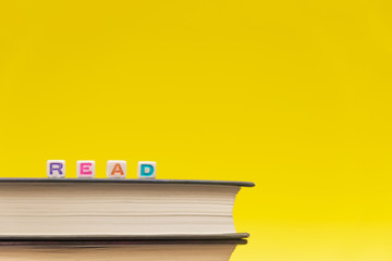 Word 'Read' written with cube colored letters on book surfase on yellow background