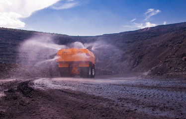 Heavy truck pours the road with water in the iron ore quarry. Dust removal, protection of the environment. Irrigation of the road from dust. The World&rsquo;s Largest Sprinkler Truck