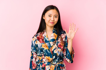 Young chinese woman wearing a kimono pajama isolated smiling cheerful showing number five with fingers.