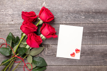 Valentine's day greeting card with red rose flowers bouquet on a vintage on gray wooden table. Top view. Copy space