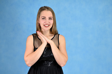 Universal concept horizontal portrait of a woman on a blue background. A photo of a pretty smiling girl with long hair and excellent make-up in a black dress stands in different poses.