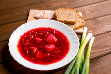 Ukrainian traditional beetroot soup - Borscht with bread, slices of bacon and onion on wooden table, food concept