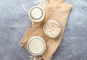 Vegan oat flakes milk, non dairy alternative milk in glass, top view, copy space