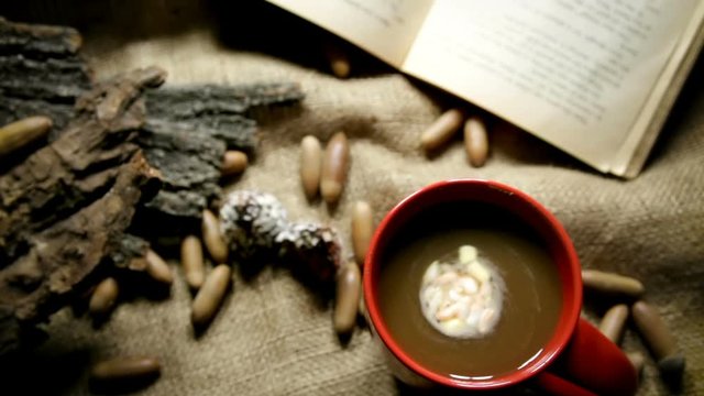 A cup of hot black coffee with sweets and acorns on canvas