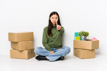 Young chinese woman moving to a new home showing number one with finger.