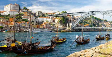 Fototapeta na wymiar Portugal, city landscape Porto, a group of yellow wooden boats with wine port barrels on Douro river, panoramic view of the old town Porto, The Eiffel Bridge view, Ponte Dom Luis, stone embankment