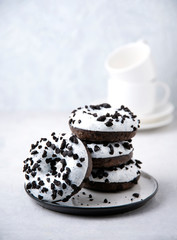several delicious fresh hearty black and white doughnuts are stacked in a white plate on a white background
