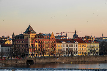 Obraz premium Sunlit old buildings in city Prague with river Vltava