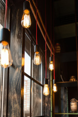 retro light bulbs on a red wire hang along a wooden window. warm glow comfort