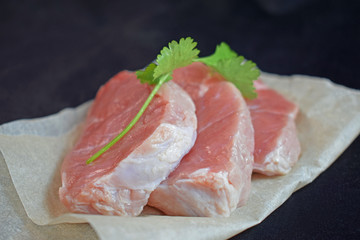 Raw meat with a sprig of green on a black background..Steak.